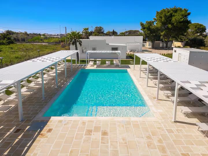 Bordo piscina di Villa Giorò con lettini e gazebo bianchi